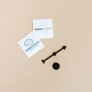 Brainworks file folder with a black spinner on a beige background, alongside branded cards.